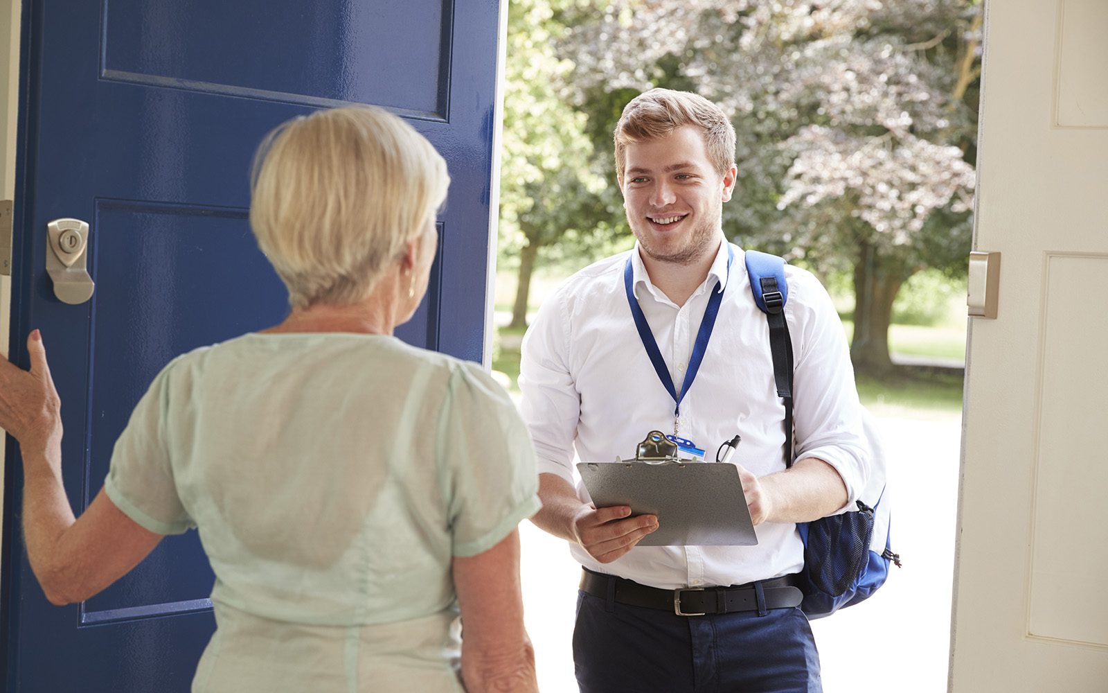 A picture of an engineer smiling at the front door with a clipboard and badge helpful sales staff identification to conduct a site survey